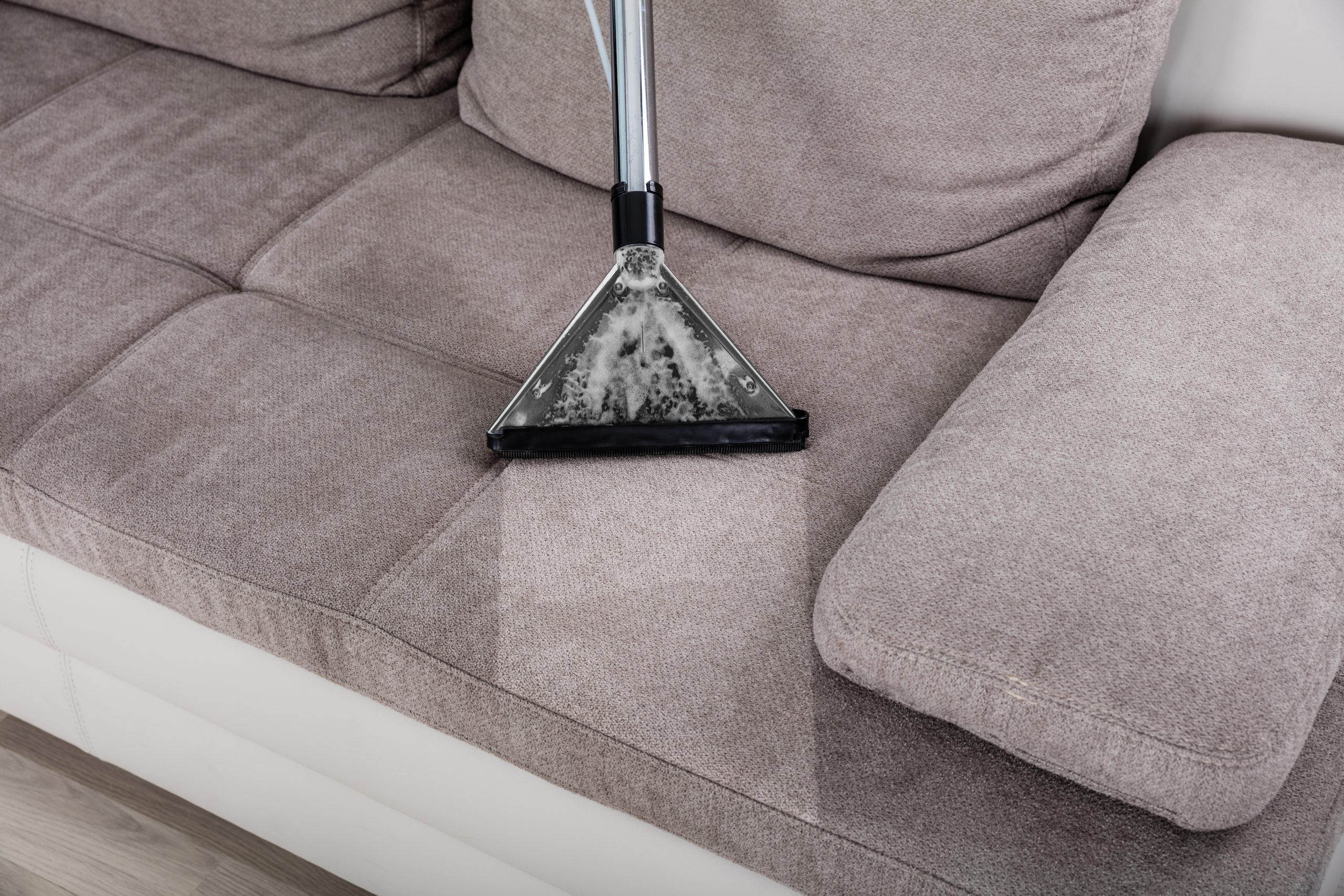 Closeup,Of,Woman,Cleaning,Sofa,With,Vacuum,Cleaner,At,Home